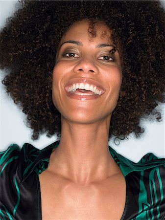 Woman with afro, smiling, head and shoulders, in studio Stock Photo - Premium Royalty-Free, Code: 693-03301145