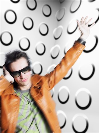 Man wearing headphones and sunglasses, blurred motion, in front of spotty wall Stock Photo - Premium Royalty-Free, Code: 693-03301178