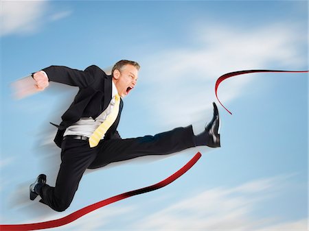 Business man jumping through red tape, digital composite Stock Photo - Premium Royalty-Free, Code: 693-03301189