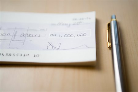 Cheque for one million dollars lying next to pen on table, close-up Stock Photo - Premium Royalty-Free, Code: 693-03301397