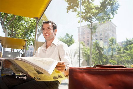 Mid-adult man reading newspaper at bus stop Stock Photo - Premium Royalty-Free, Code: 693-03301434