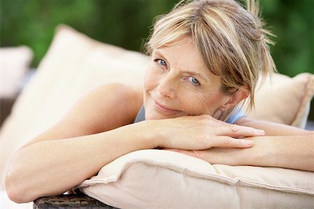 Middle-aged woman sitting on sofa in garden, portrait Stock Photo - Premium Royalty-Free, Code: 693-03301707