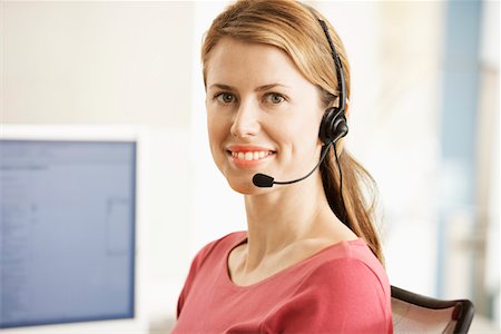 simsearch:693-03564532,k - Mid-adult female office worker sitting in cubicle wearing headset, portrait Stock Photo - Premium Royalty-Free, Code: 693-03301735