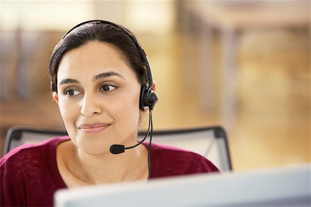 simsearch:693-03564532,k - Mid-adult female office worker sitting in cubicle wearing headset, portrait Stock Photo - Premium Royalty-Free, Code: 693-03301736