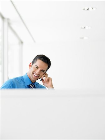 simsearch:693-03307925,k - Homme d'affaires souriant au bureau sur téléphone portable Photographie de stock - Premium Libres de Droits, Code: 693-03302004