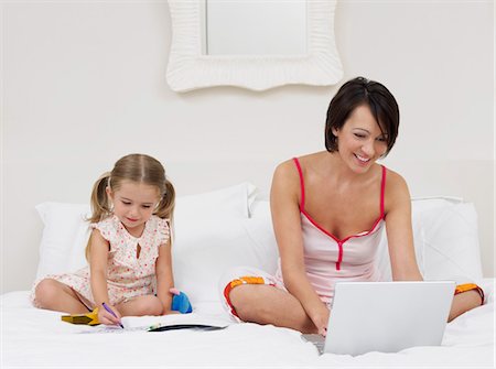 Mother and daughter drawing and using laptop on bed Stock Photo - Premium Royalty-Free, Code: 693-03302329