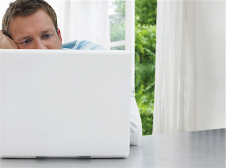 Man staring at laptop, window and garden behind Stock Photo - Premium Royalty-Free, Code: 693-03302343