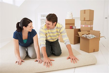 Couple unrolling carpet in new home Stock Photo - Premium Royalty-Free, Code: 693-03302692