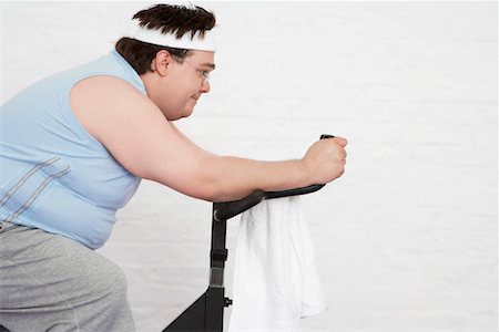 Overweight man on Exercise Bike, side view Stock Photo - Premium Royalty-Free, Code: 693-03302948