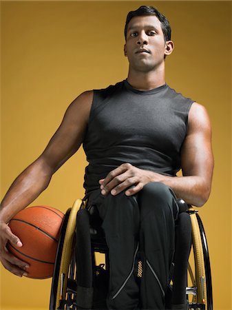 paraolimpionici - Paraplegic athlete sitting in wheelchair holding basketball Fotografie stock - Premium Royalty-Free, Codice: 693-03302973