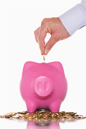 Man putting money in overflowing piggy bank, close up of hand Foto de stock - Royalty Free Premium, Número: 693-03303060