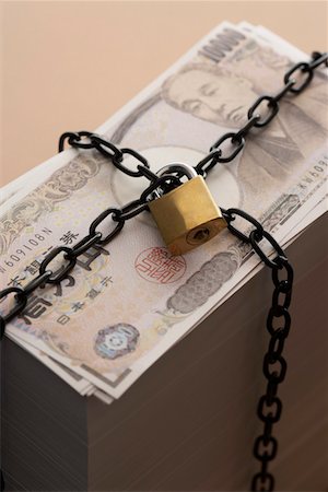 Stack of notes secured by padlock and chain Stock Photo - Premium Royalty-Free, Code: 693-03303071