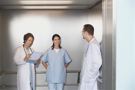 Physicians in Elevator talking Foto de stock - Sin royalties Premium, Código: 693-03303173