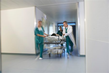 Doctors running Patient on gurney through hospital corridor, motion blur Stock Photo - Premium Royalty-Free, Code: 693-03303213