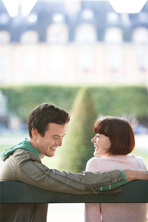 paris lovers bench - Young couple sitting on bench, looking over shoulder, in park Stock Photo - Premium Royalty-Free, Code: 693-03303348