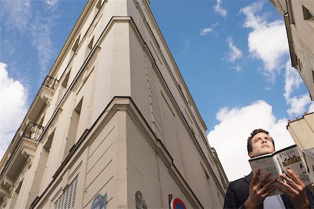 Paris, France, Man with guide book in front of apartment blocks Fotografie stock - Premium Royalty-Free, Codice: 693-03303363