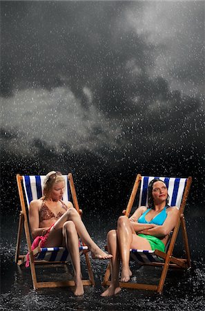 Sunbathers sitting in sunloungers during downpour Stock Photo - Premium Royalty-Free, Code: 693-03303418