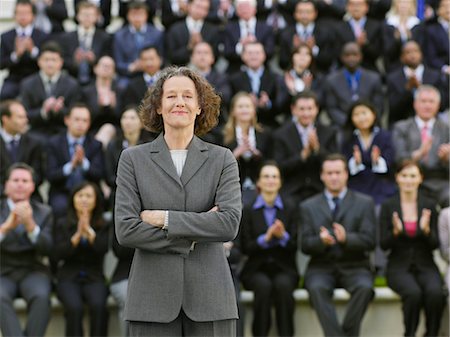 standout - Business woman standing in front of business people sitting in bleachers, clapping, portrait Stock Photo - Premium Royalty-Free, Code: 693-03303477