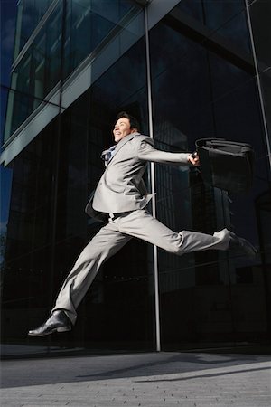 Businessman holding briefcase Jumping outside building Foto de stock - Sin royalties Premium, Código: 693-03303528