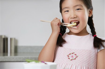 Young Girl with pigtails Eating Baby Corn with chopsticks Stock Photo - Premium Royalty-Free, Code: 693-03303547