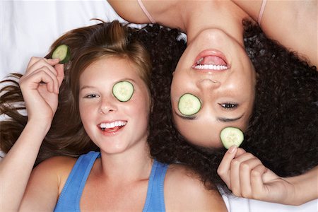 simsearch:693-03303563,k - Teenage Girls lying on backs with cucumbers in eyes, overhead view Foto de stock - Sin royalties Premium, Código: 693-03303566