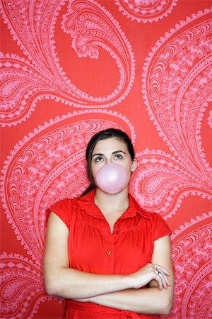 Teenaged girl blowing bubble against pink and red patterned wallpaper Stock Photo - Premium Royalty-Free, Code: 693-03303569