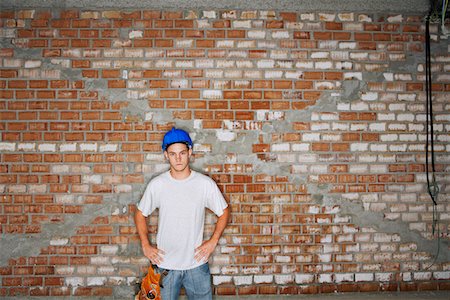 Young construction worker standing by brick wall Stock Photo - Premium Royalty-Free, Code: 693-03303619