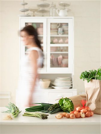 shopping bags in kitchen - Woman walking behind Fresh Produce on Kitchen Counter, side view Stock Photo - Premium Royalty-Free, Code: 693-03303680