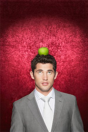 Man with apple on head against red velvet background Stock Photo - Premium Royalty-Free, Code: 693-03303784