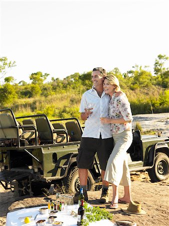 Couple on picnic during safari, smiling, jeep in background Stock Photo - Premium Royalty-Free, Code: 693-03303960