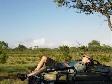 Homme d'âge adulte se trouvant sur le capot de la jeep, ayant nap Photographie de stock - Premium Libres de Droits, Code: 693-03303990