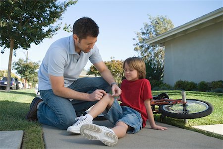 dad and son on bike - Father looking after son, bicycle laying on floor Stock Photo - Premium Royalty-Free, Code: 693-03314075