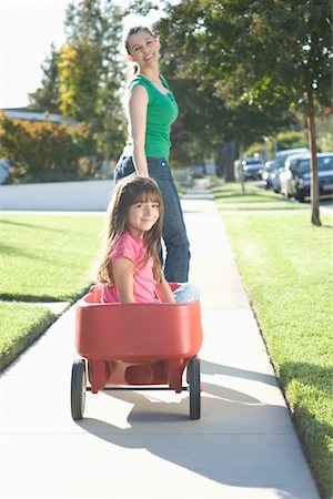 suburban family lifestyle - Mother pulling daughter in trolley Stock Photo - Premium Royalty-Free, Code: 693-03314076