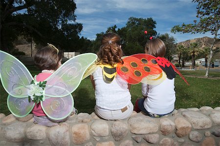Three girls (7-12) wearing costumes, sitting in park Stock Photo - Premium Royalty-Free, Code: 693-03314098