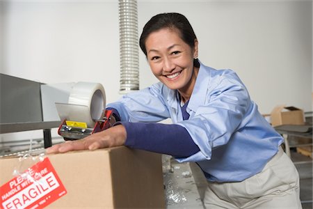 simsearch:693-03315351,k - Cheerful Asian woman working in distribution warehouse Foto de stock - Royalty Free Premium, Número: 693-03315340