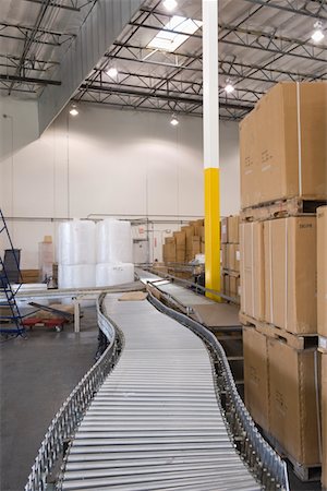 Cardboard boxes and conveyor belt in distribution warehouse Fotografie stock - Premium Royalty-Free, Codice: 693-03315350