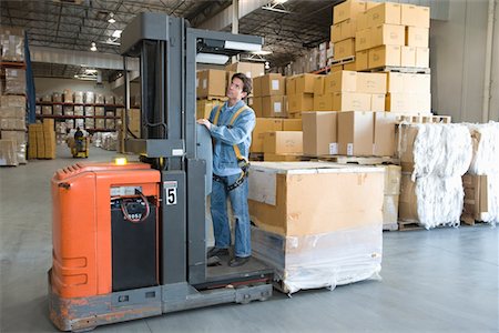 simsearch:693-03315379,k - Man operating fork lift truck in distribution warehouse Foto de stock - Royalty Free Premium, Número: 693-03315382