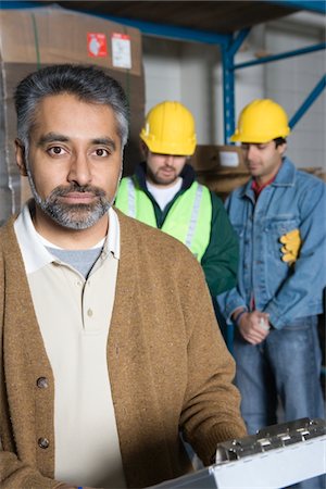 ethnic factory worker - Serious men in factory, colleagues in background Foto de stock - Sin royalties Premium, Código: 693-03315396