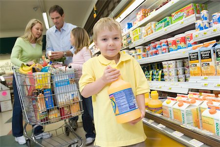 Young boy holds orange juice while family shop in supermarket Stock Photo - Premium Royalty-Free, Code: 693-03315604