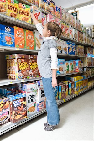 Young girl reaching for ceral product in supermarket aisle Stock Photo - Premium Royalty-Free, Code: 693-03315631