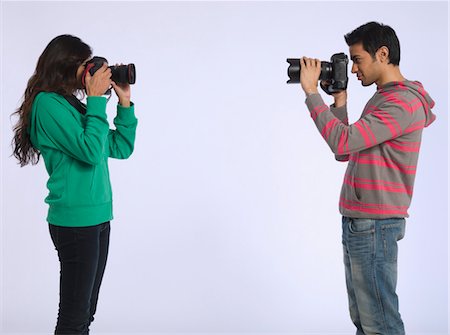 dslr-camera - Young woman and young man photographing each other, studio shot Stock Photo - Premium Royalty-Free, Code: 693-03316380