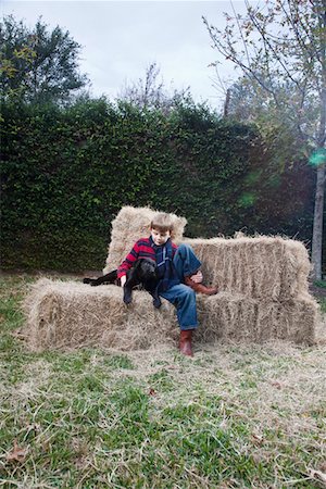Boy with dog on hay bale Stock Photo - Premium Royalty-Free, Code: 693-03316484