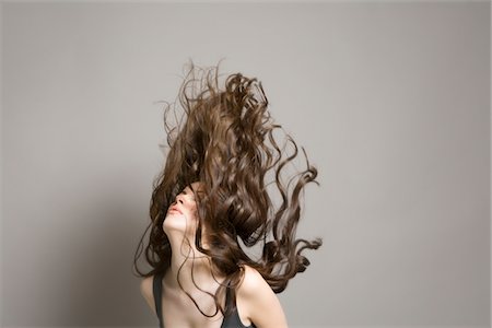 Woman tossing long brown wavy hair Stock Photo - Premium Royalty-Free, Code: 693-03316537