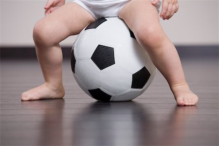 Baby boy sitting on soccer ball Stock Photo - Premium Royalty-Free, Code: 693-03316824