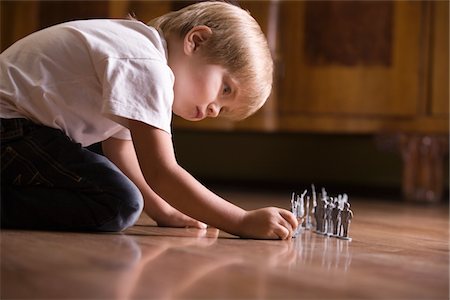 Boy playing with toy soldiers on floor Stock Photo - Premium Royalty-Free, Code: 693-03317020