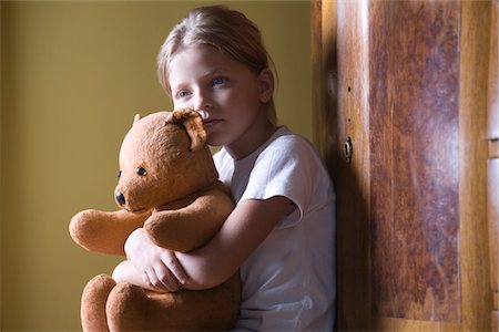 sad child toy - Girl embracing teddy bear in home Stock Photo - Premium Royalty-Free, Code: 693-03317034