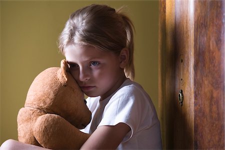 sad child toy - Girl embracing teddy bear in home Stock Photo - Premium Royalty-Free, Code: 693-03317033