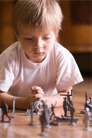 sad child toy - Boy playing with toy soldiers on floor Stock Photo - Premium Royalty-Free, Code: 693-03317041