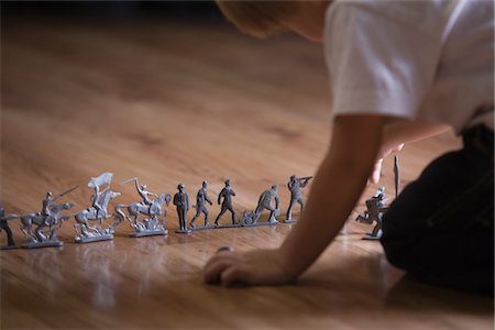 Boy playing with toy soldiers on floor Stock Photo - Premium Royalty-Free, Code: 693-03317042