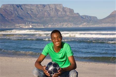 Jeune homme au football sur la plage de la montagne de la Table Photographie de stock - Premium Libres de Droits, Code: 693-03317491